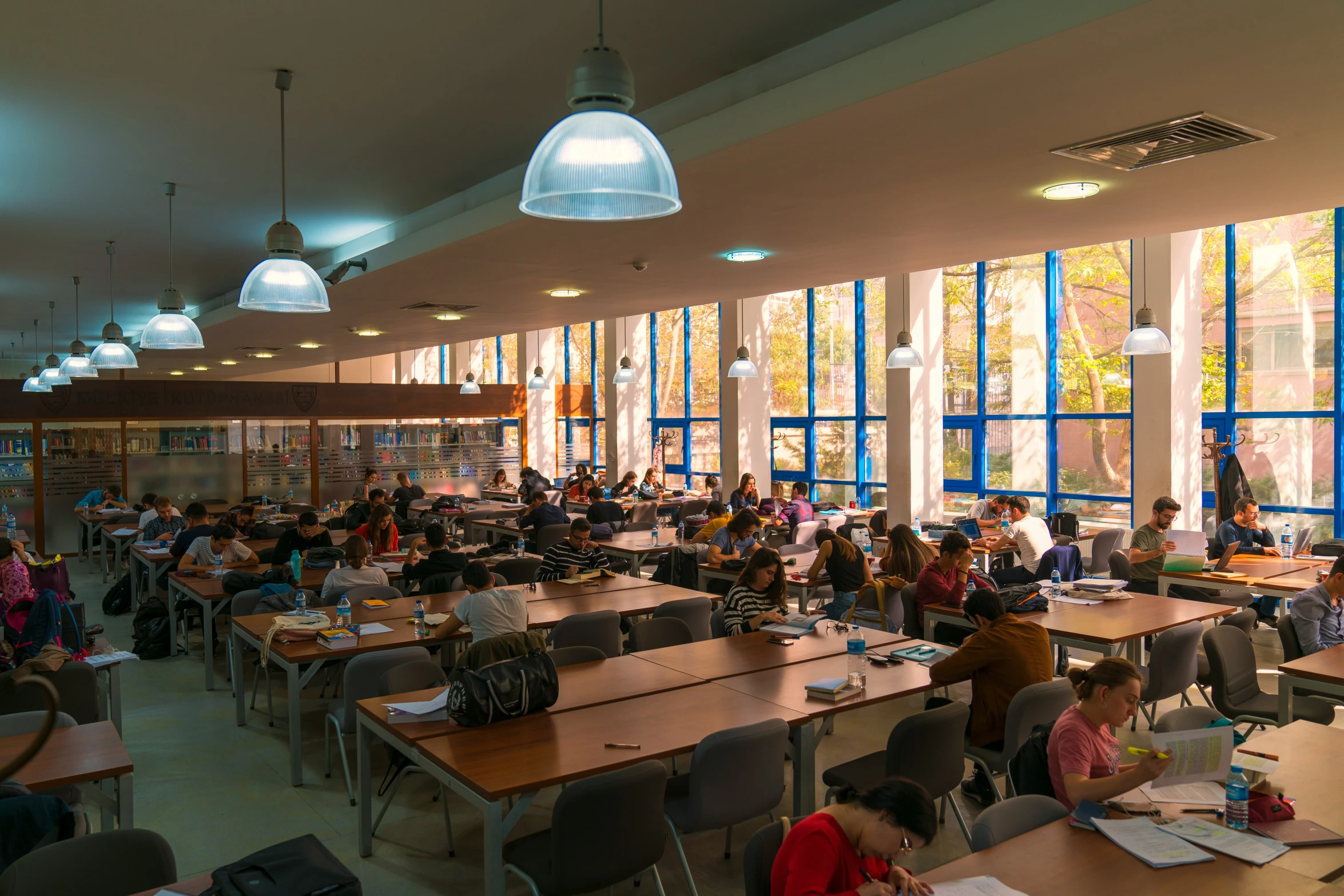 a classroom with students studying at tables and hanging lamp