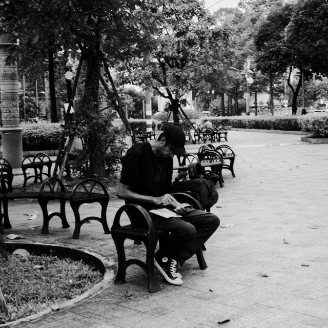 man sitting on park bench looking at paper