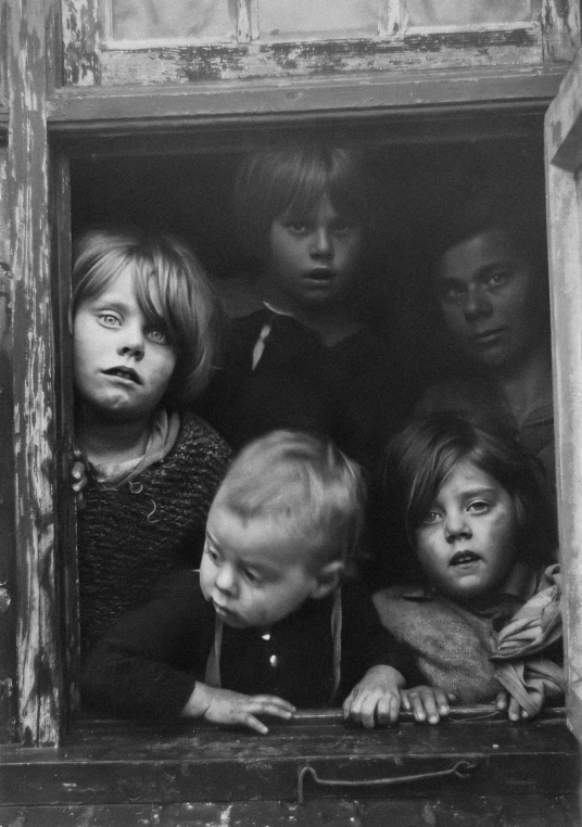 four children peeking out a window together