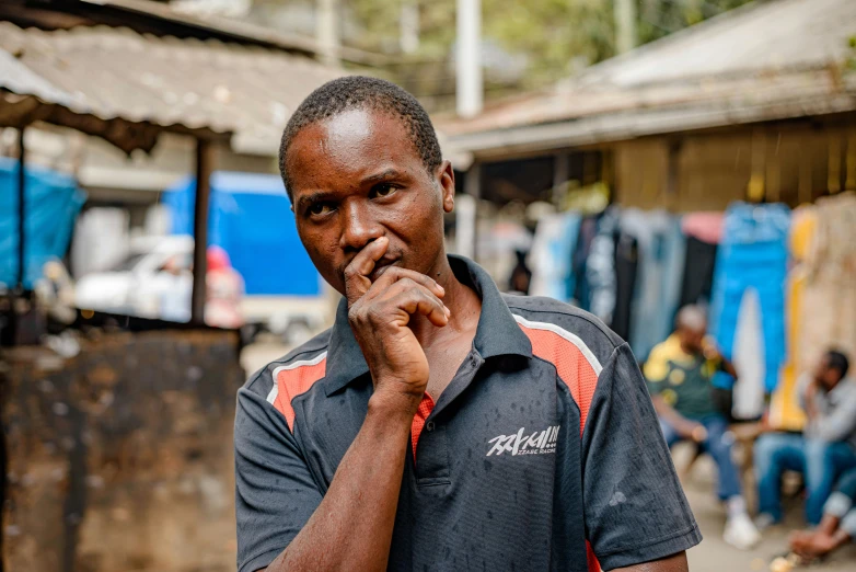 the man stands in front of his shack with people outside