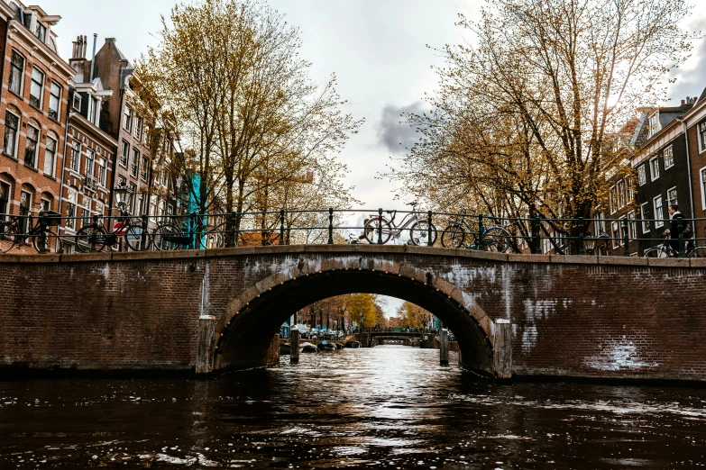 an old bridge above a small river with trees on both sides