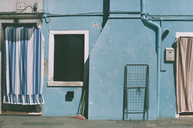 the blue exterior of the house has some open curtains