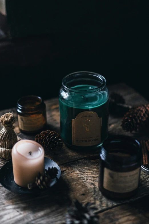 a glass jar filled with green liquid next to pine cones