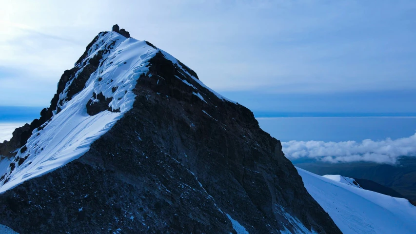 two mountain peaks covered in snow on a cloudy day