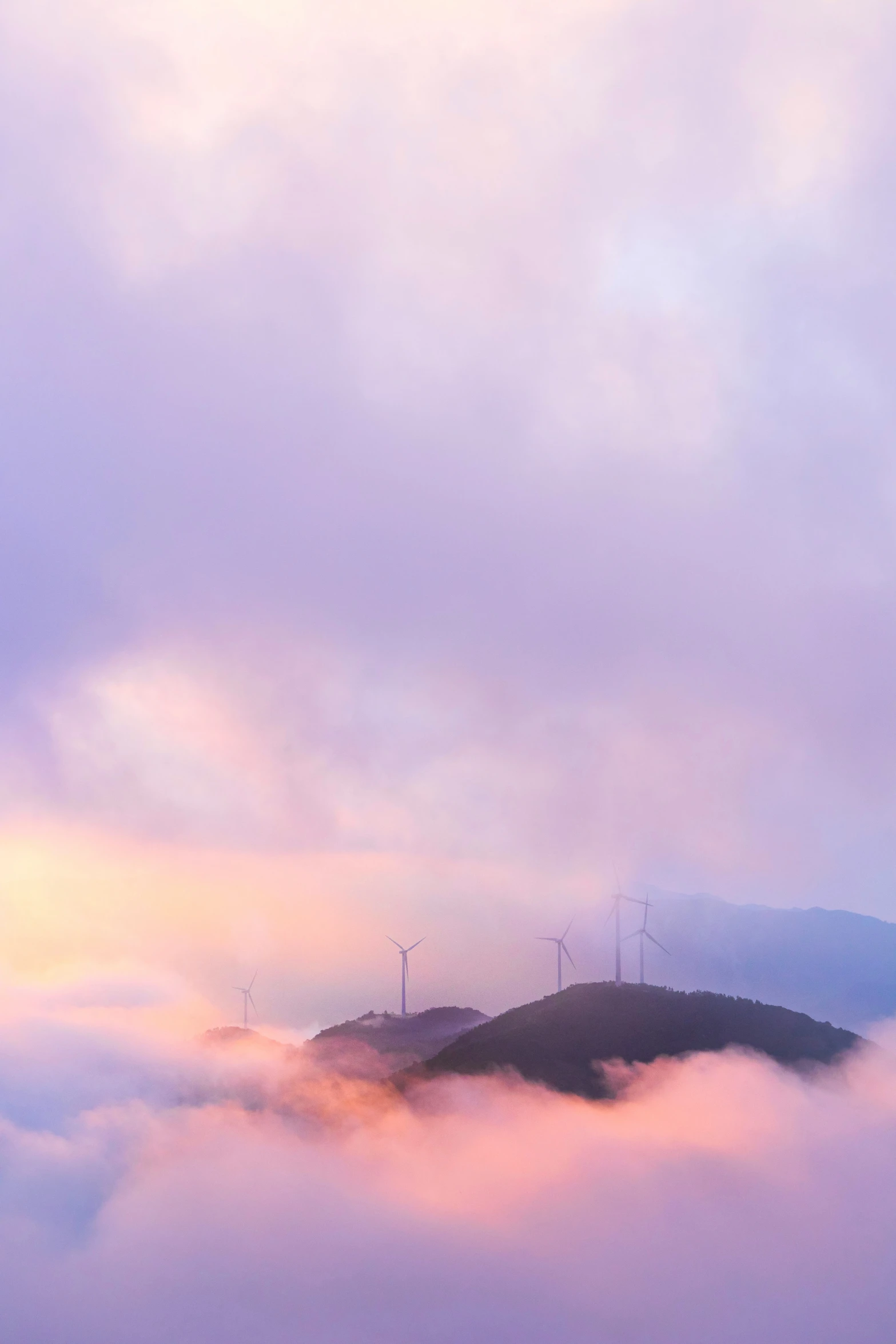 a mountain top with a small hill on it is covered in a cloud