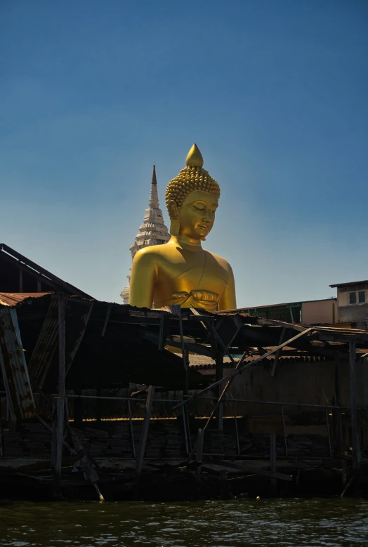 an image of a golden buddha statue on the river