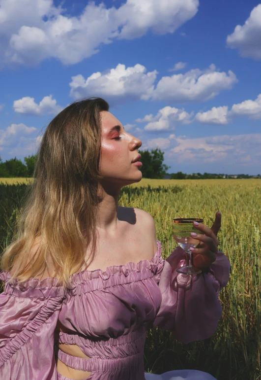 a woman with an orange painted face sits in a field of wheat