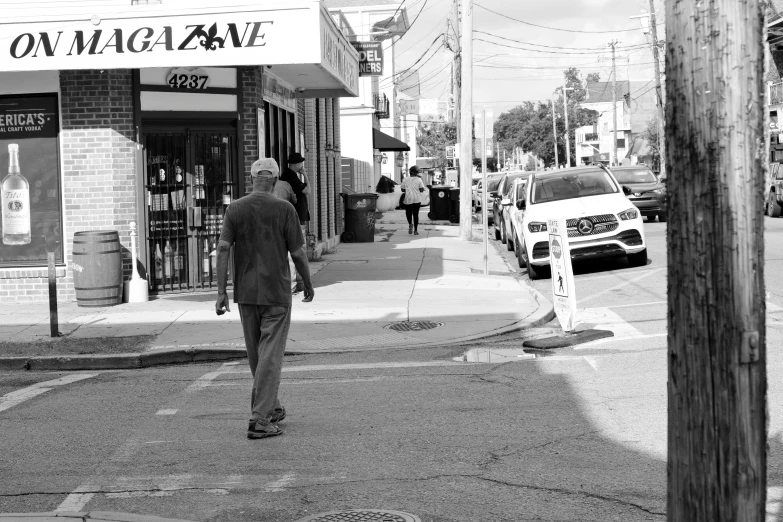 a man walking down the road near a liquor store