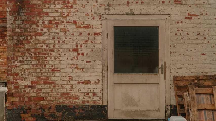 an old red brick building has a door and some wood crates