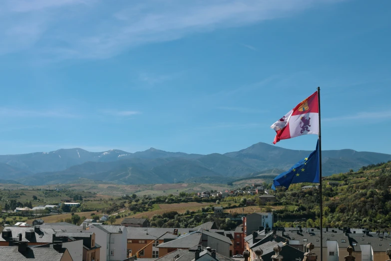 a flag and mountain peaks over small village with a town