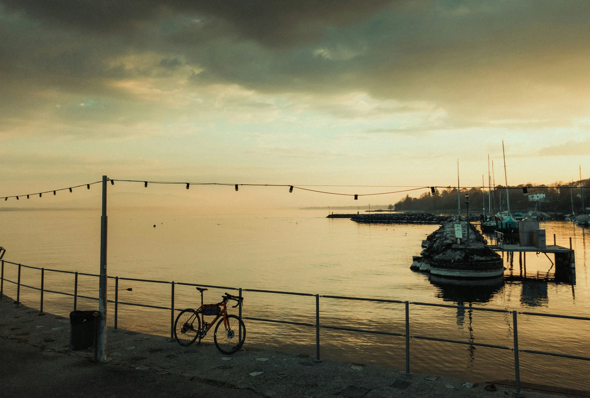 a view over the water from an area covered by a fence and bicycles