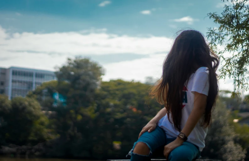 a woman with long hair sitting on a park bench