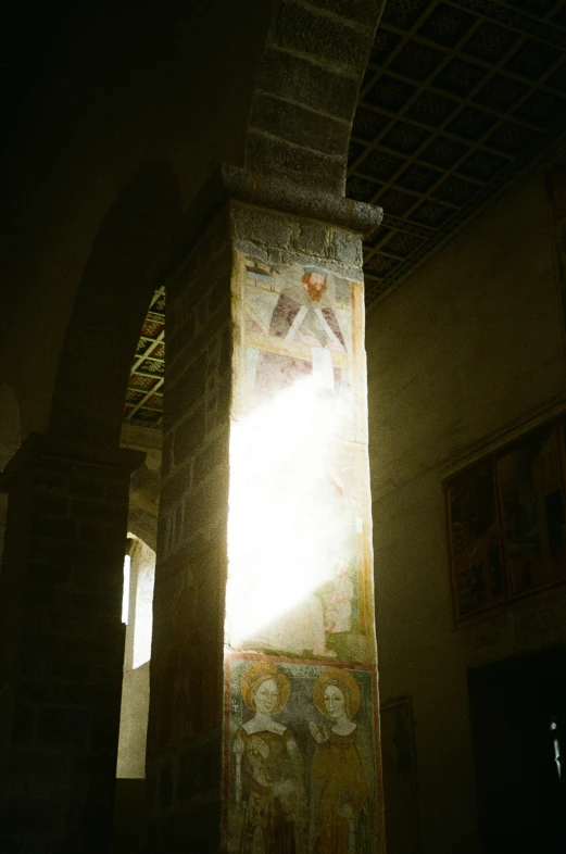 a sun shining through a doorway with a painting on the wall