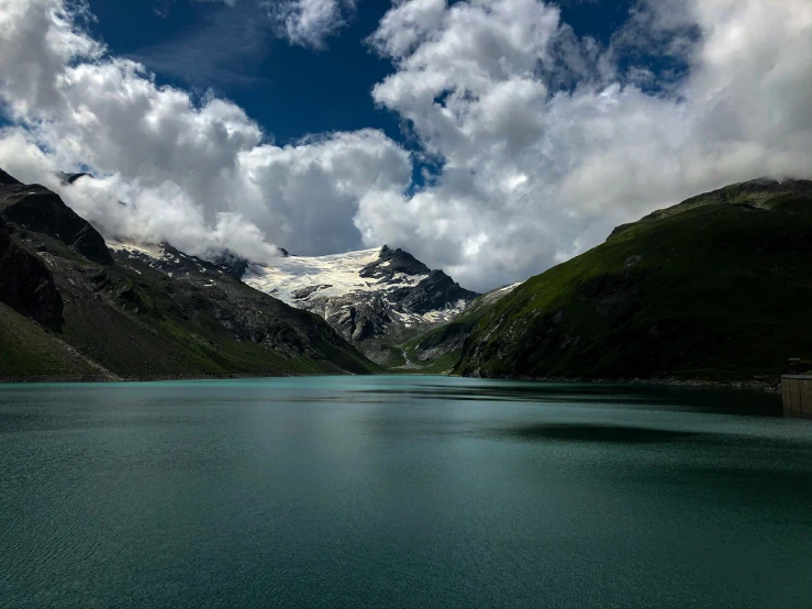 a blue lake is surrounded by mountains and clouds