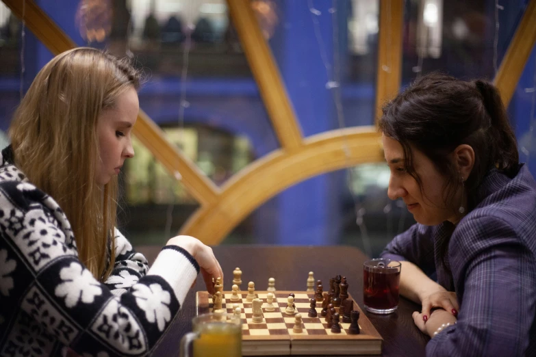 two girls sitting at a table playing chess