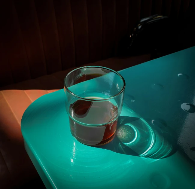 a glass of drink sitting on top of a green table