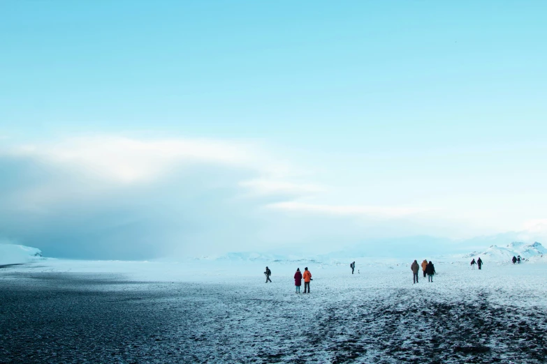 several people walk across an expanse of snow