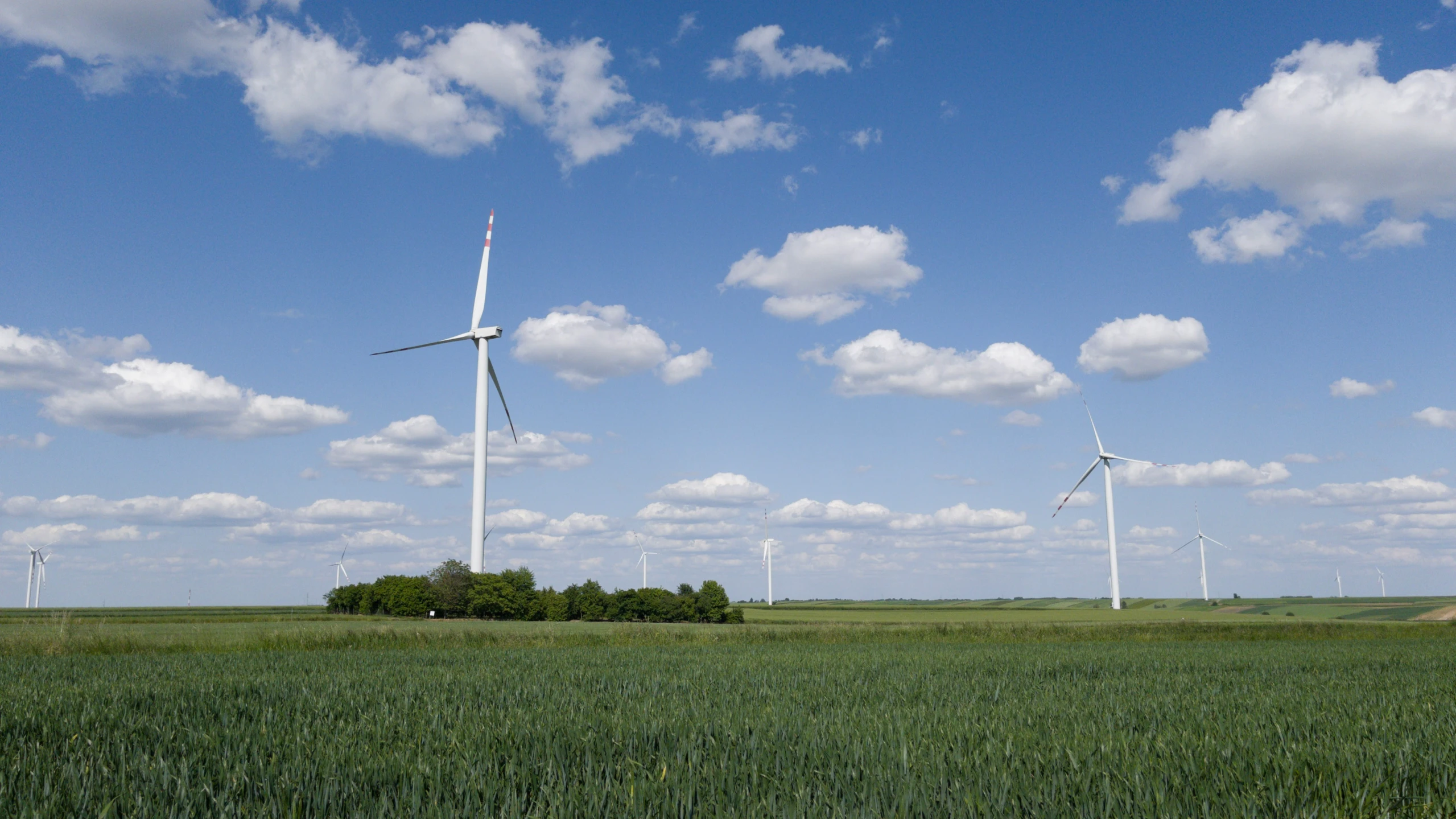 several wind mills near a farm on a cloudy day