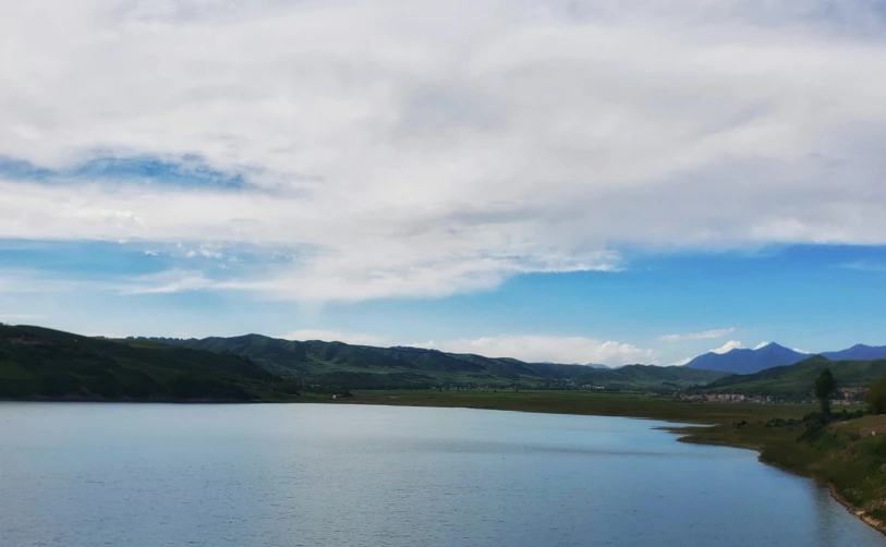 the sky is over the water with mountains on it