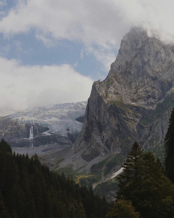 a tall mountain covered in trees and clouds