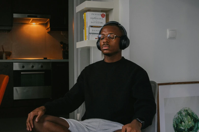 a man sitting in front of an open microwave while wearing headphones