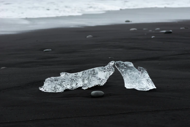 two broken bottles are on the beach next to the water