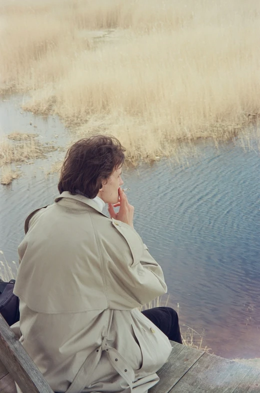 a person sitting on the edge of a dock talking on a cell phone