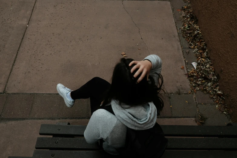 a girl sitting on a bench on the side walk