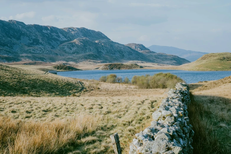 a grassy field with hills and water in the distance