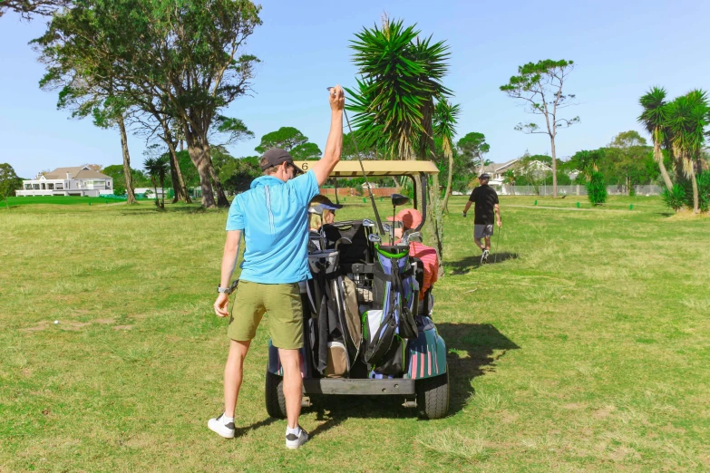 a man is putting golf gear in a cart