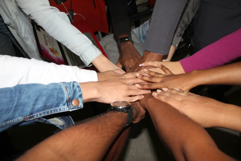 many people are putting their hands in the middle of a circle