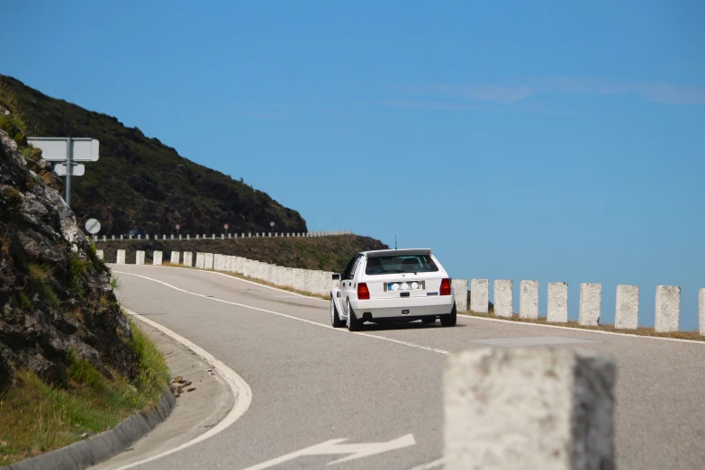 a car sitting on the side of a hill, facing an ocean