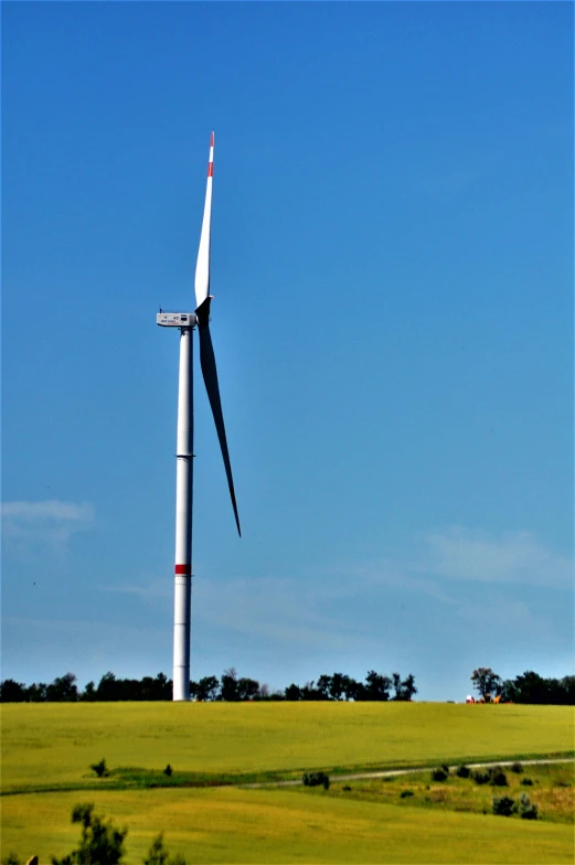 a large wind turbine on top of a grass covered hill