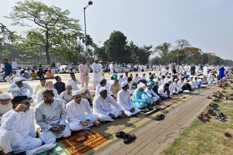 a group of men sit on the ground in front of a row of people