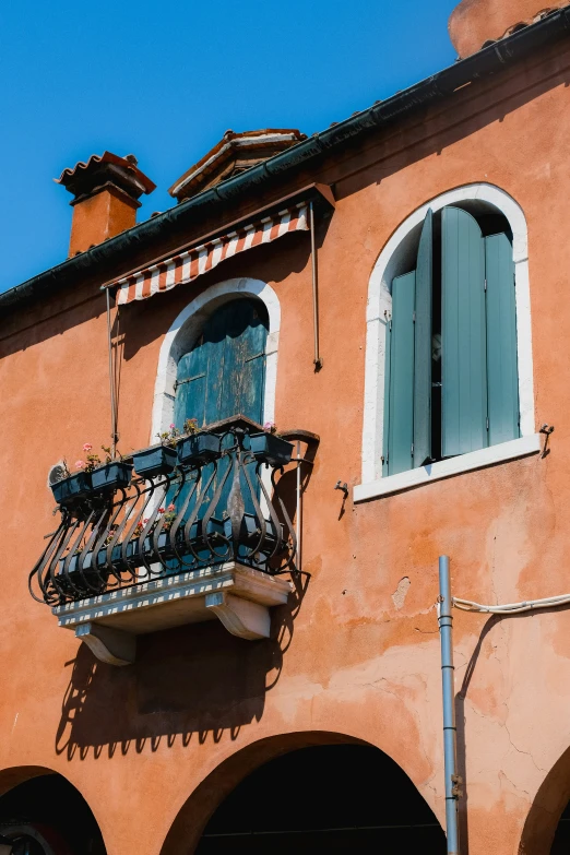 a red brick building with an iron balcony and shutters