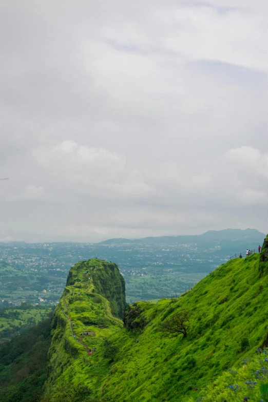 a lush green hill with tall rock formations