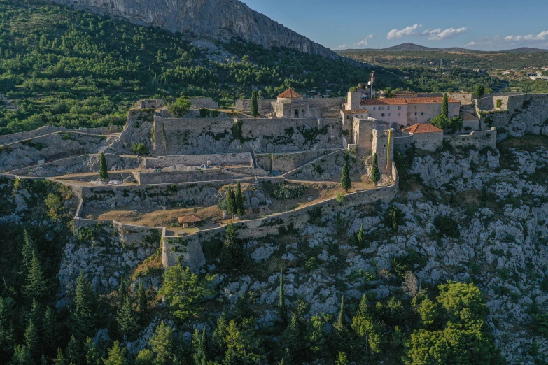 a city on the side of a cliff surrounded by trees