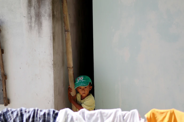 a  with a green hat on looking out a window