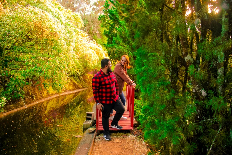 two people on the side of a river surrounded by trees