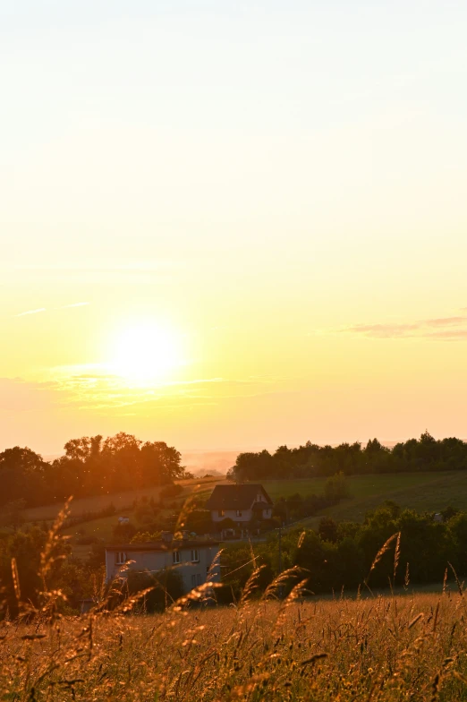 the view of a sunset over farmland with a distant village