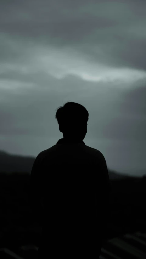 a man is staring at the mountains on a cloudy day