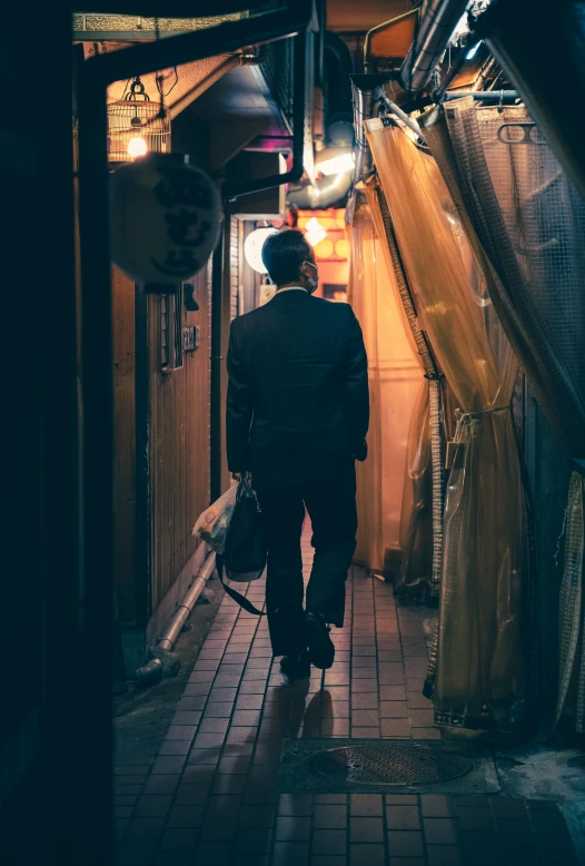 a man walks down a narrow alley with a hat on