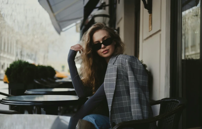 a woman leaning against a table wearing glasses