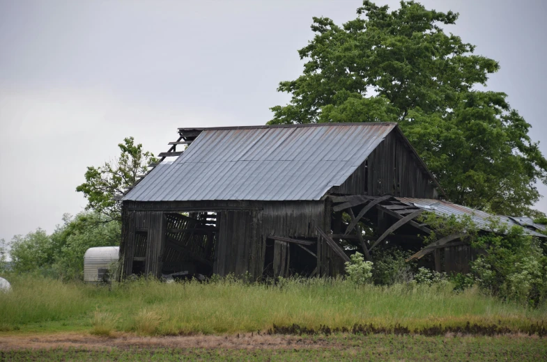an old barn sitting in the middle of a green field