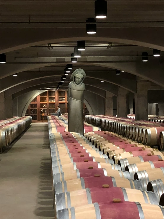 rows of wooden barrel racks line a wine room filled with wine glasses