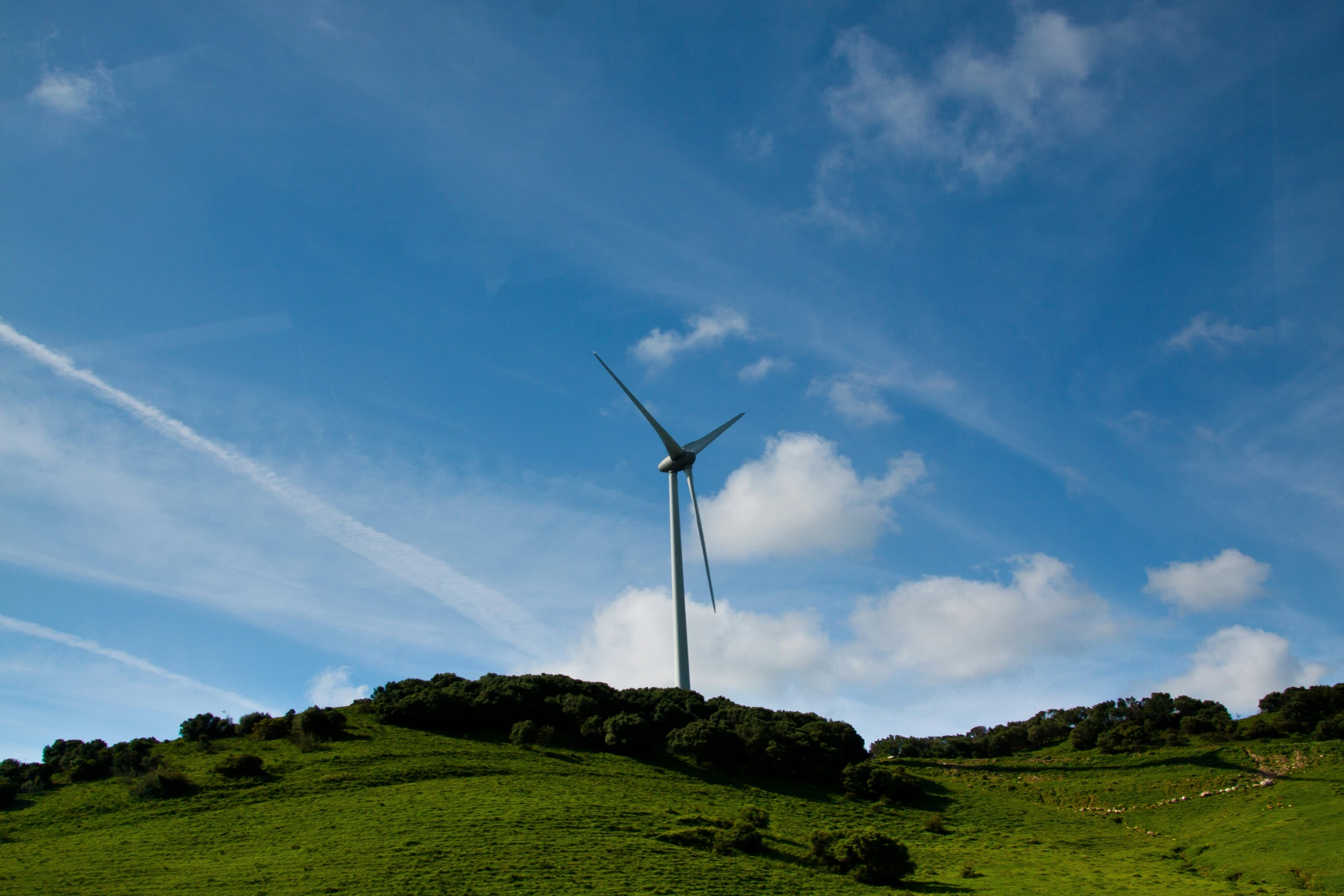 a wind turbine is visible on top of a hill