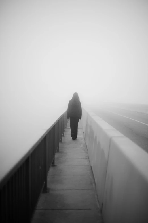 a man walking down the middle of a walkway next to a wall