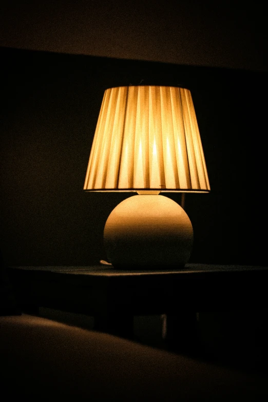 the lamp is lit on the table in the dark