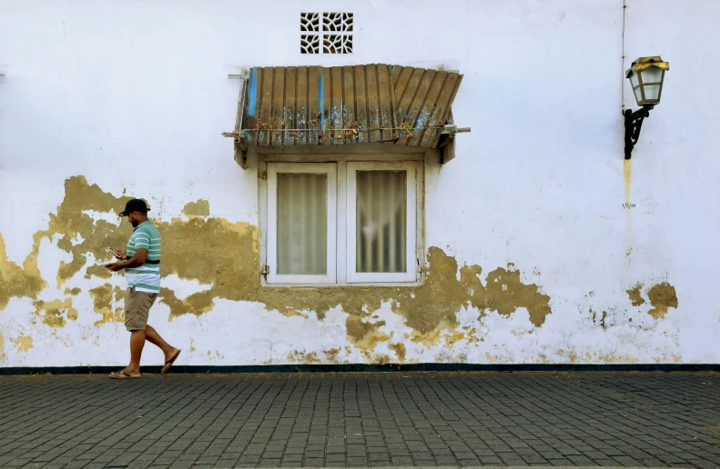 the man is walking down the street in front of the building