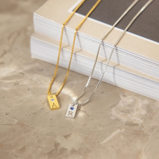 three silver and gold necklaces are sitting on a table